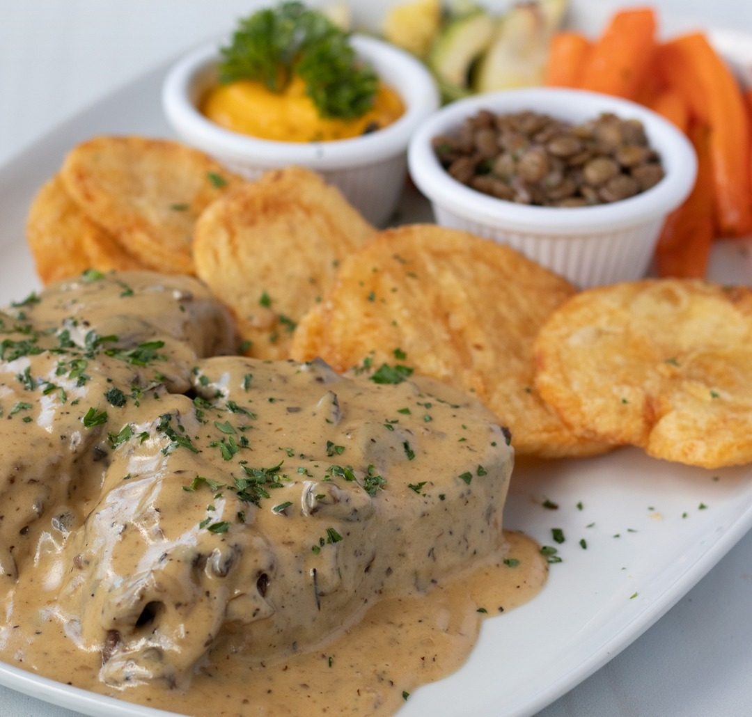 Medallón bañado en salsa cremosa de hongos con papas doradas, puré de camote y lentejas