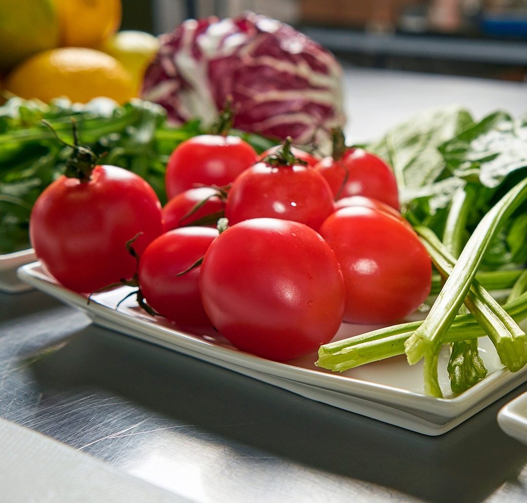 Tomates frescos, hojas verdes y radicchio sobre el mesón de acero de la cocina