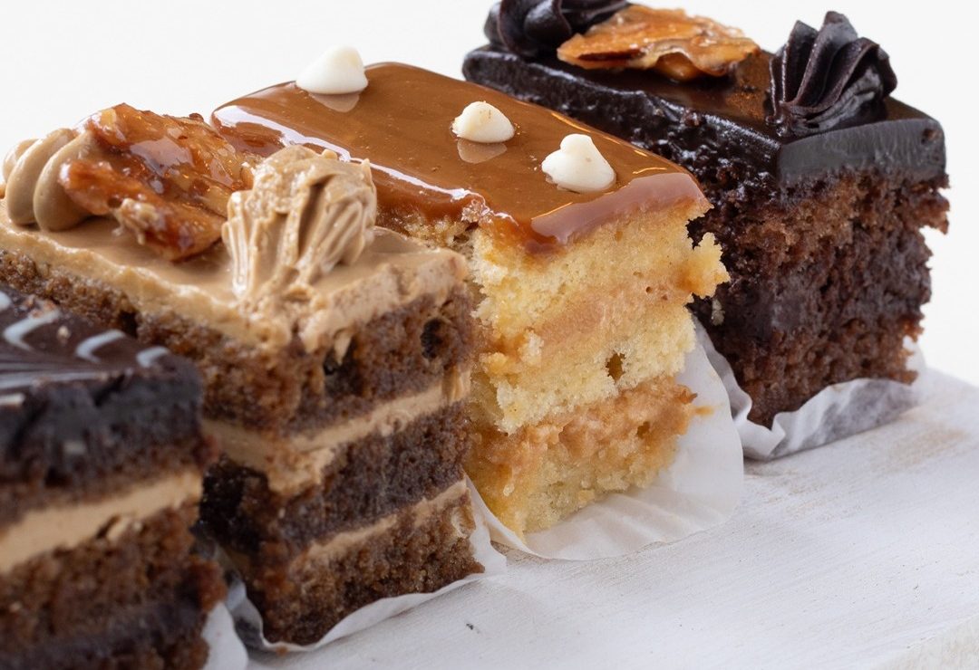 Tres porciones de pastel en capas, de caramelo y de chocolate, sobre papel encerado
